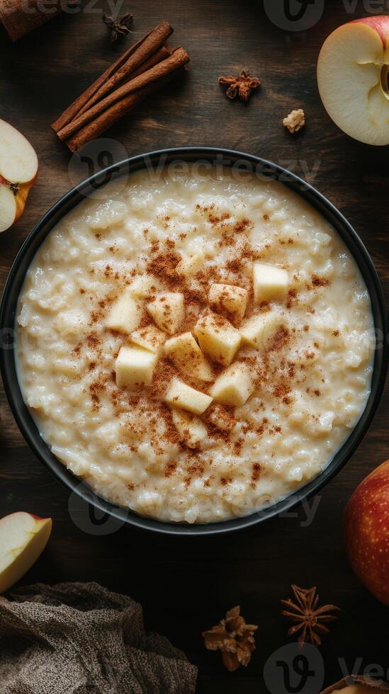 Warm bowl of creamy oatmeal topped with diced apples and cinnamon on a rustic wooden table photo