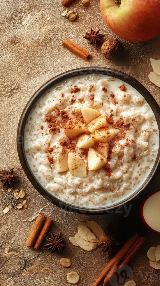 Warm oatmeal bowl topped with cinnamon, apple slices, and nuts displayed on a rustic surface photo