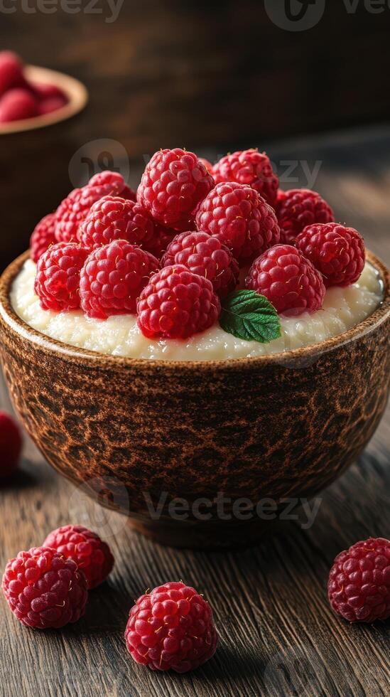 Creamy dessert topped with fresh raspberries in a rustic bowl on a wooden table photo