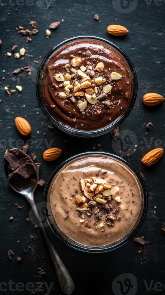 Delicious chocolate and vanilla dessert cups topped with crushed nuts served on a dark stone surface photo