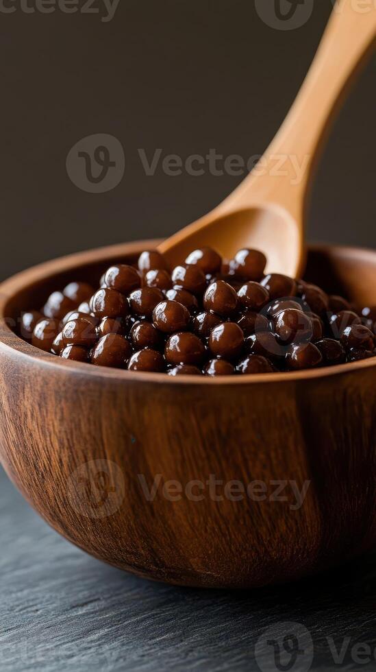 Delicious chocolate tapioca pearls in a wooden bowl with a spoon on a dark background photo