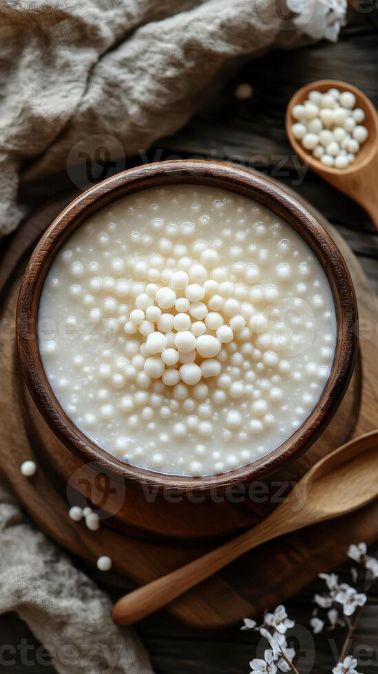 Delicious tapioca pearls in creamy dessert served in a rustic wooden bowl with a spoon photo