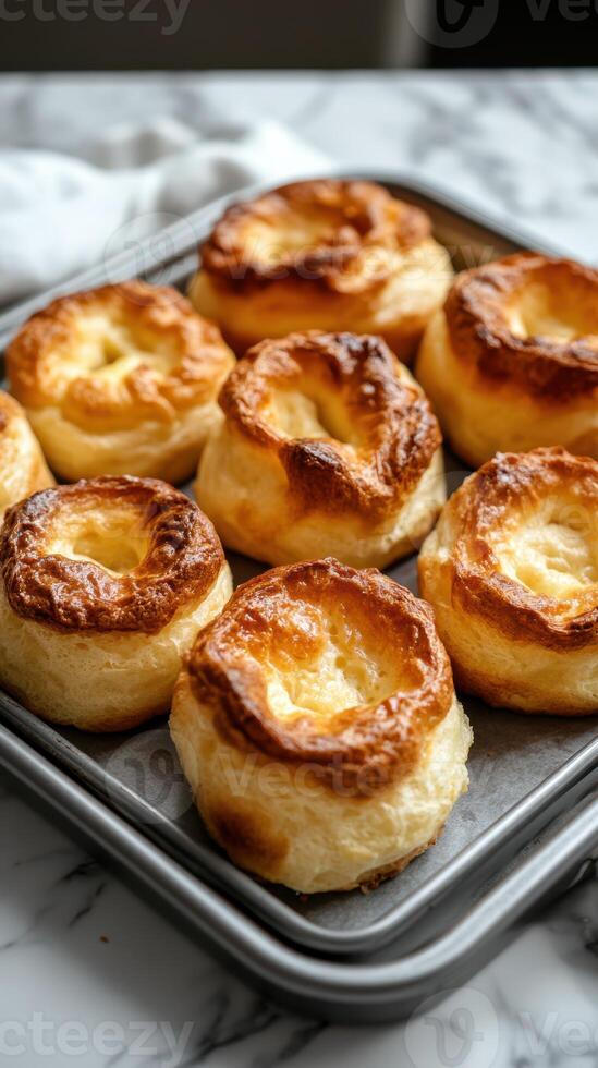 Freshly baked golden pastries arranged neatly on a baking tray on a marbled countertop photo