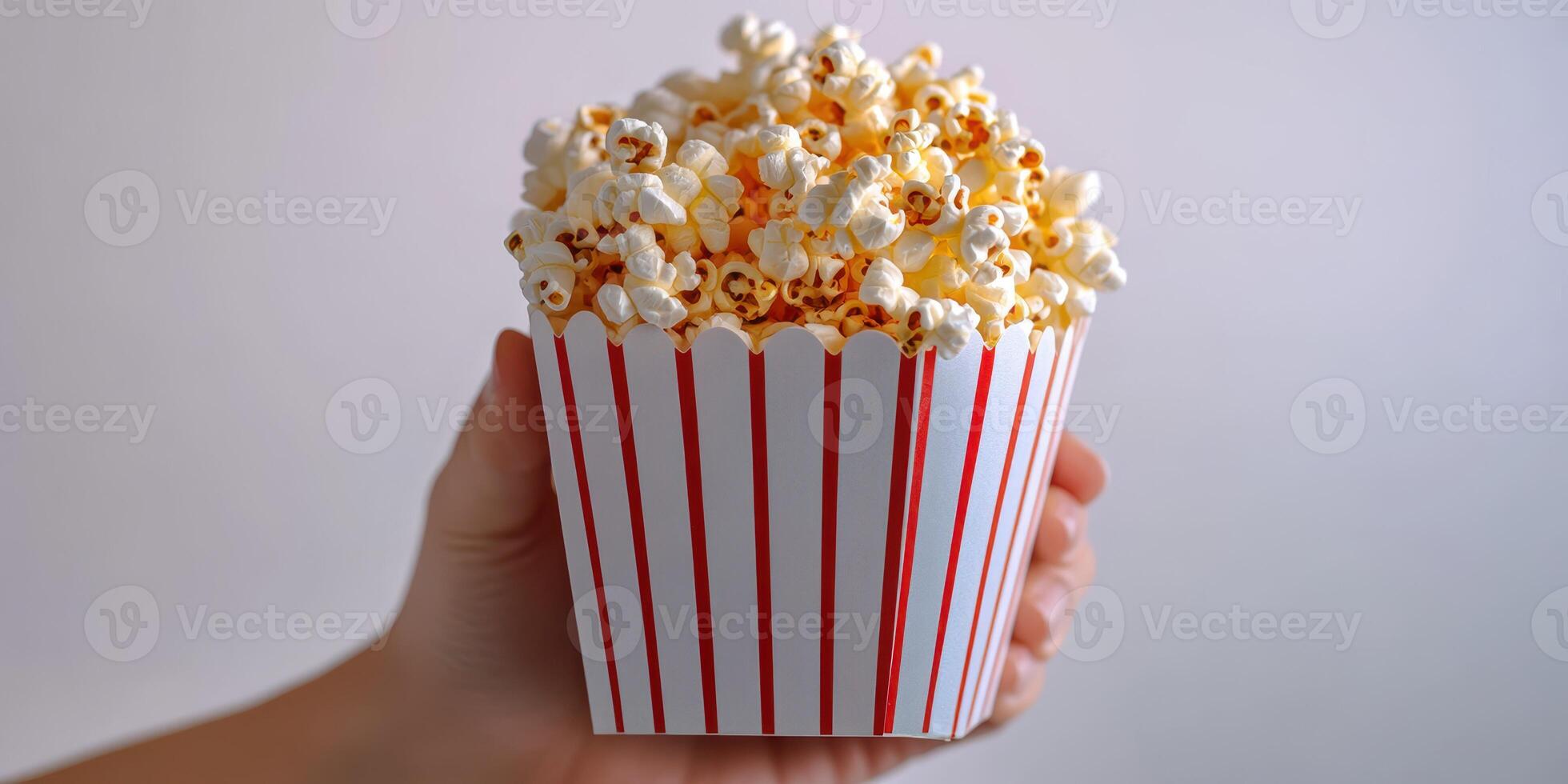 Freshly popped popcorn served in a classic striped container ready for movie night enjoyment at home photo