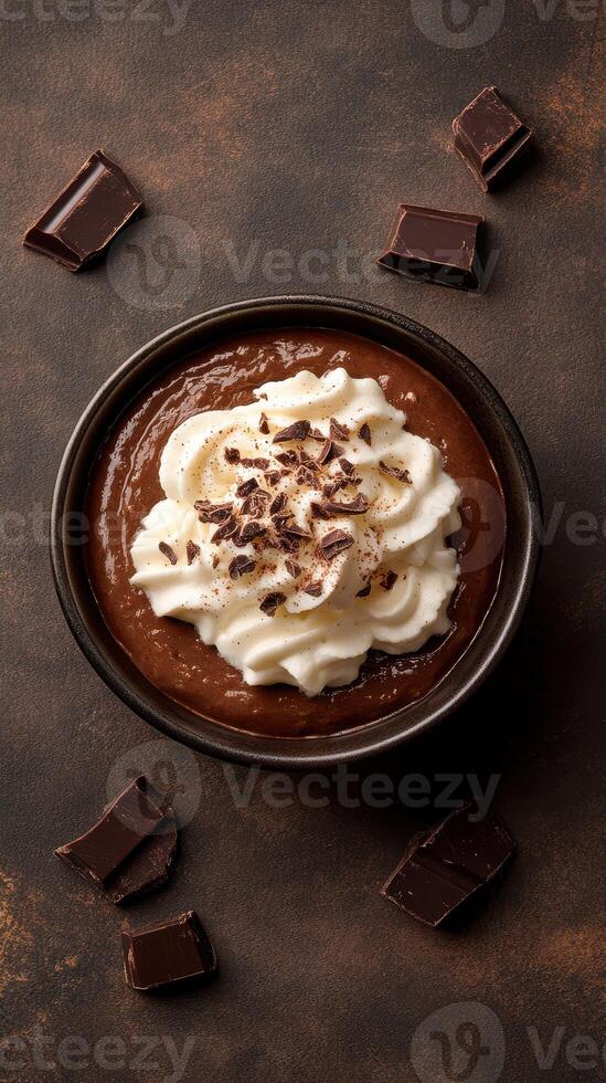 Rich chocolate dessert topped with whipped cream and chocolate shavings in a dark bowl photo