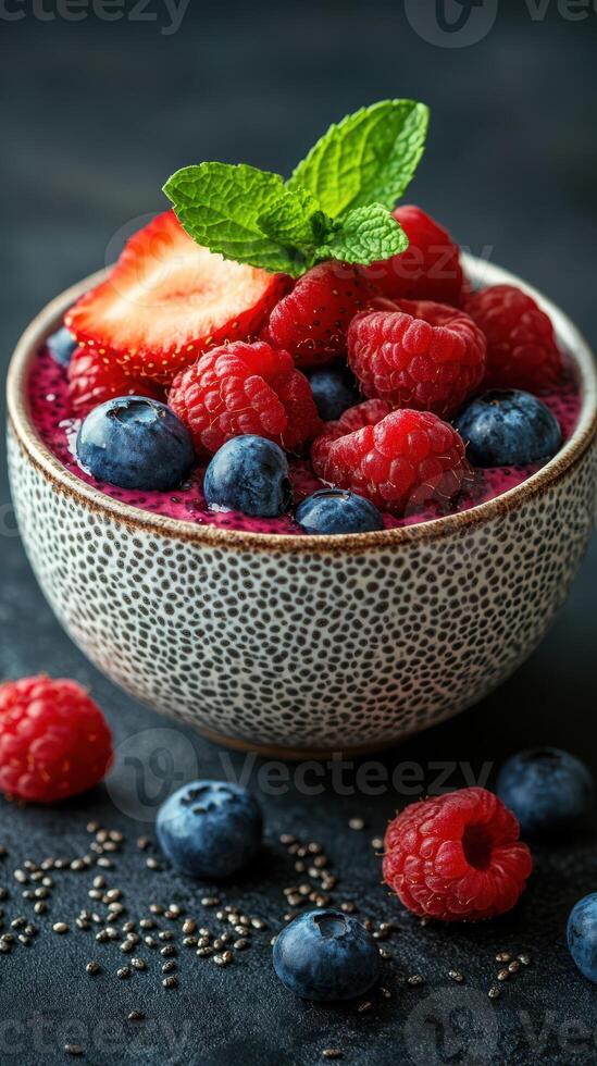 Colorful bowl of mixed berries with chia seeds and mint on a dark textured surface photo