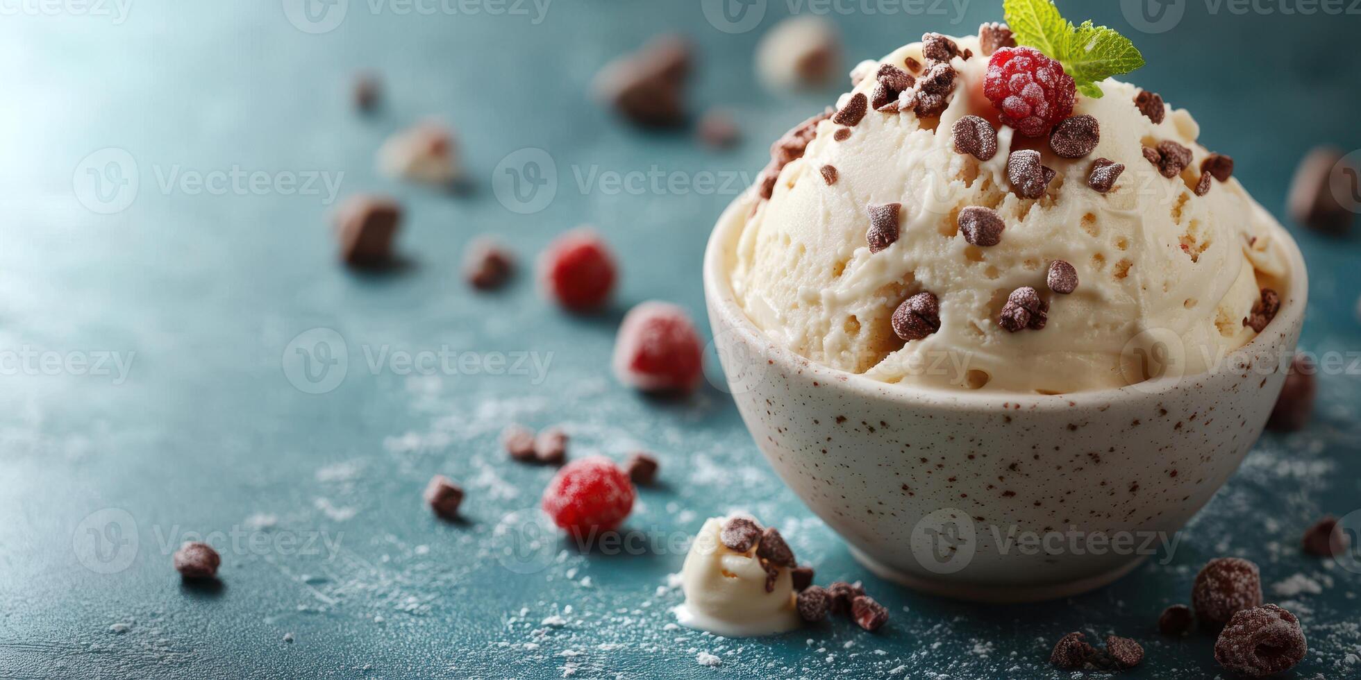 Indulgent bowl of vanilla ice cream topped with chocolate shavings and raspberries on a textured surface photo
