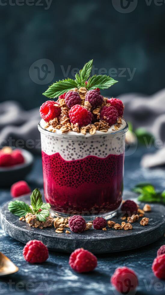 Delicious dessert with layers of chia pudding, raspberry compote, and granola garnished with fresh berries and mint photo