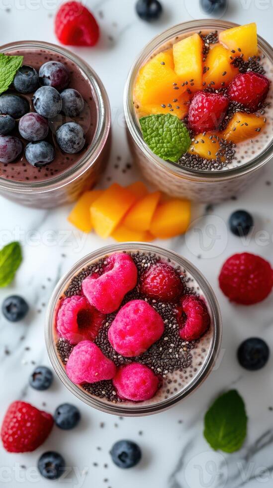 Colorful dessert jars filled with chia pudding topped with fresh fruits at a kitchen table photo