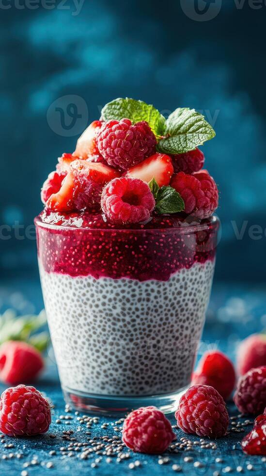 Chia pudding topped with fresh raspberries and strawberry compote in a glass photo