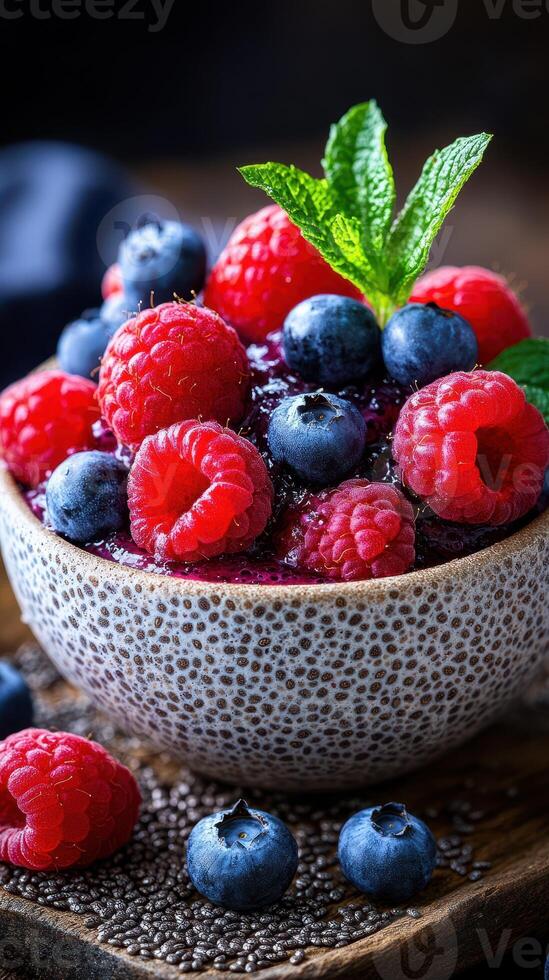 Fresh berries in a textured bowl with mint leaves on a wooden surface showcasing vibrant colors photo