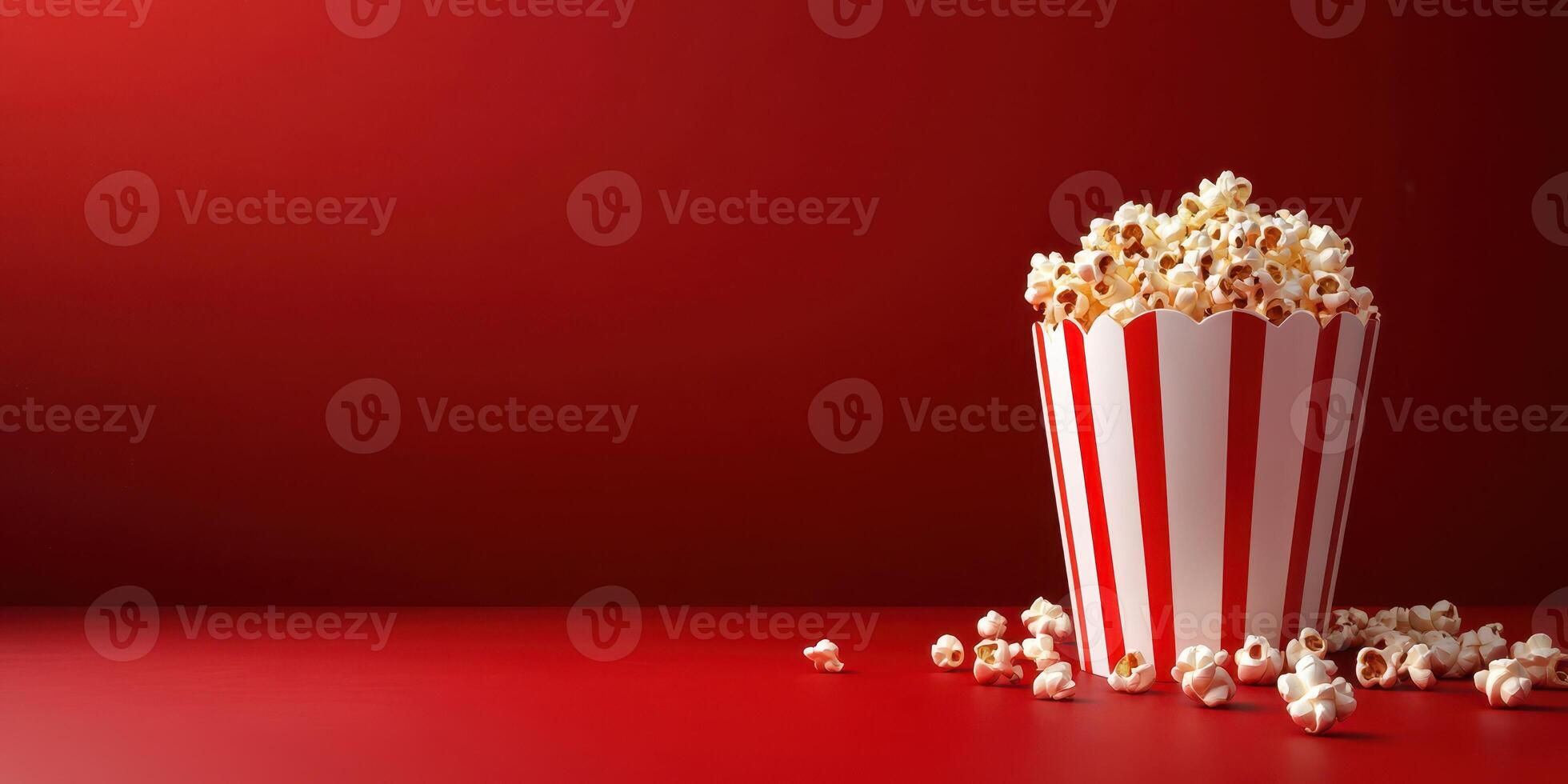 Freshly popped popcorn in a striped container on a vibrant red background perfect for movie night snacks photo