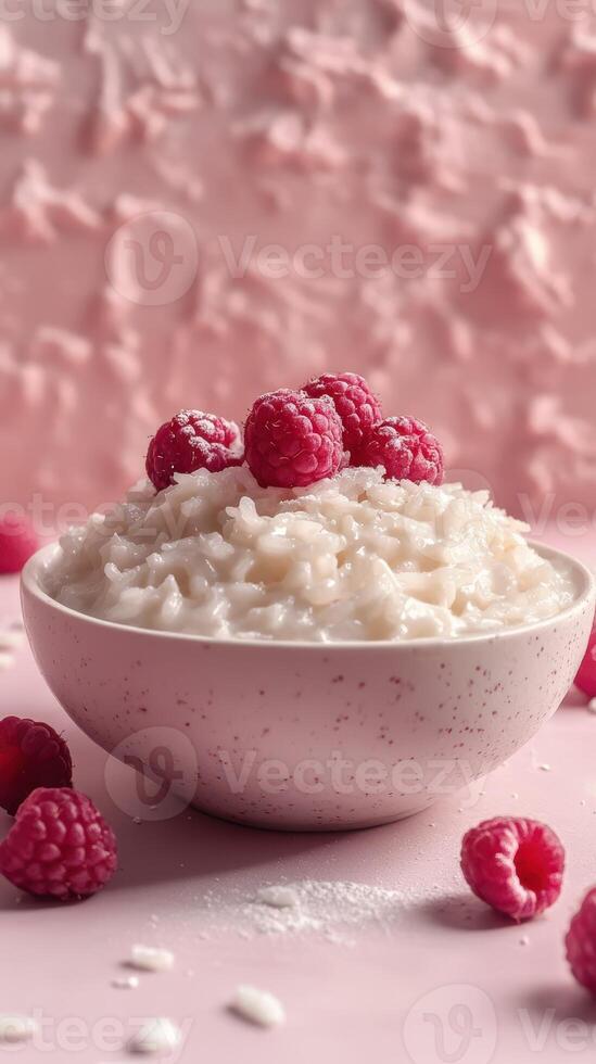 Creamy rice pudding topped with fresh raspberries on a soft pink background photo