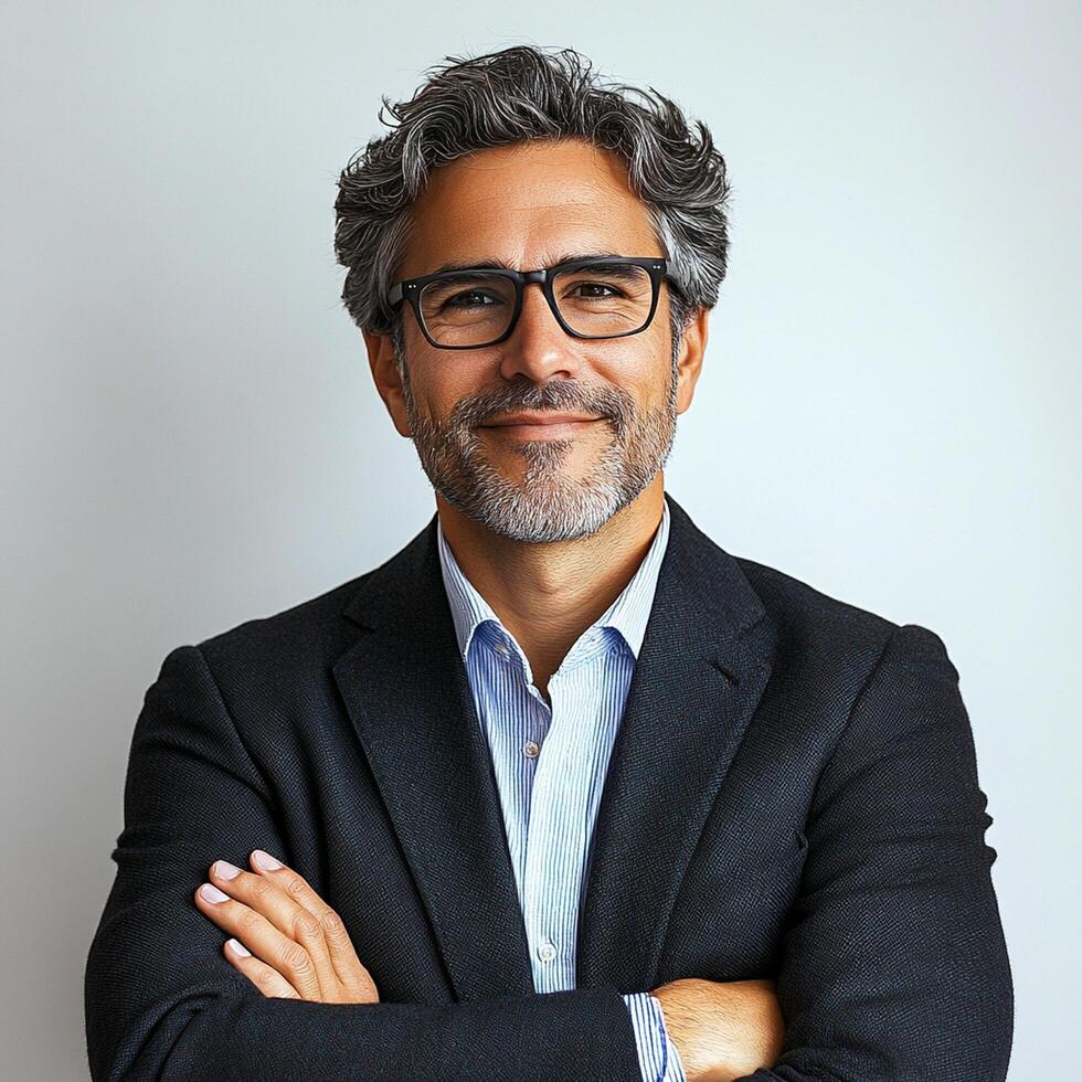 A man with glasses and a beard is standing with his arms crossed photo