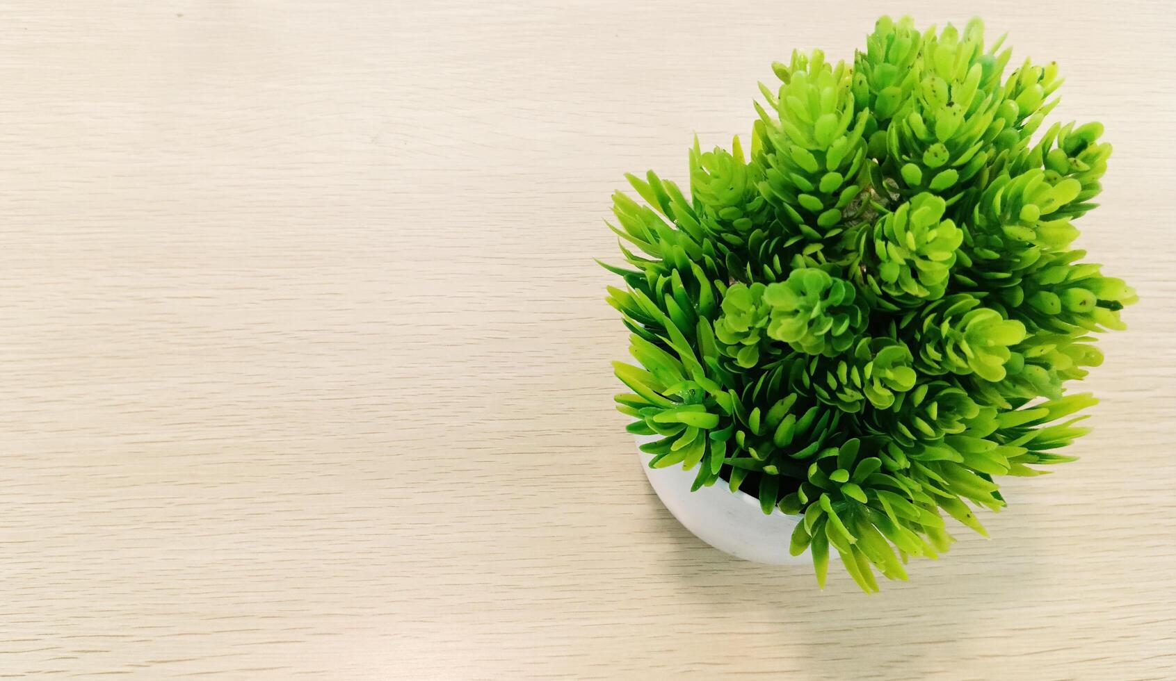 Artificial plastic grass in a pot on the right on a light colored wooden background. photo