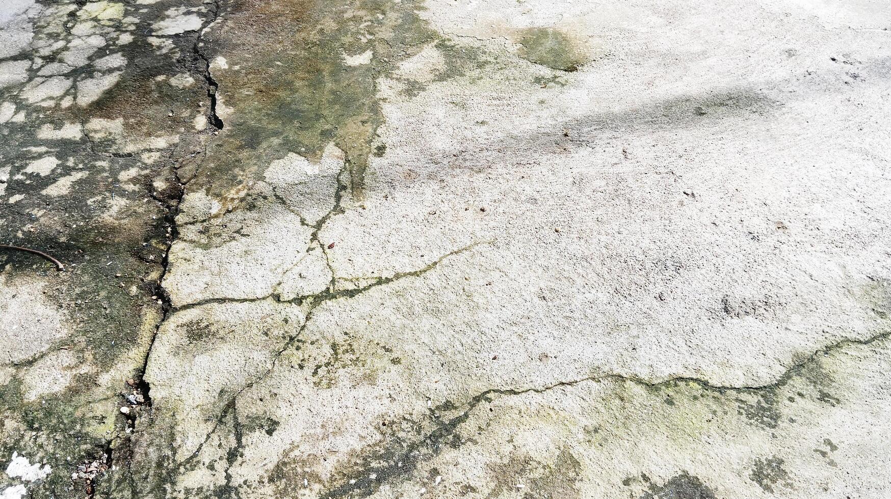 Irregular mossy cracked cement floor texture with close-up photo. photo