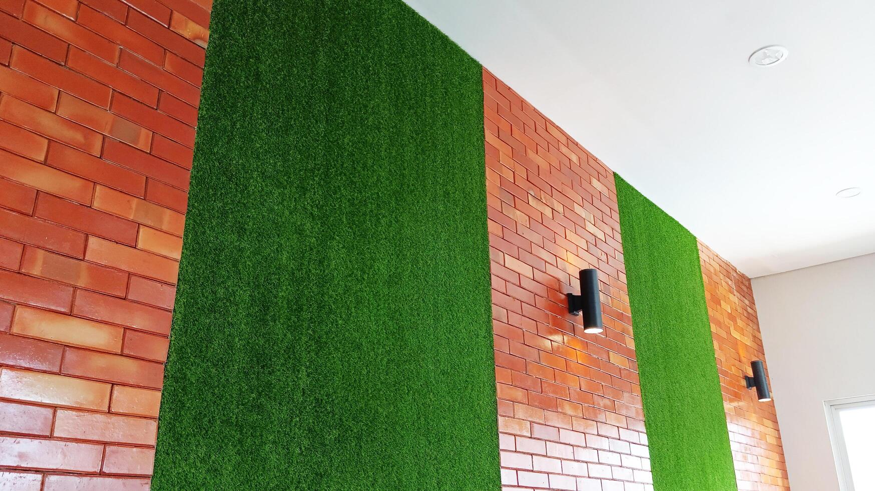 The building with synthetic grass interior and exposed red brick is decorated with several garden lights. photo