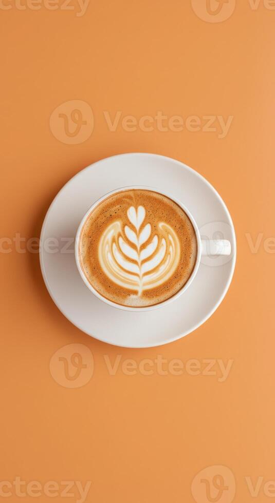 A cup of coffee with a leaf pattern on top of an orange background photo
