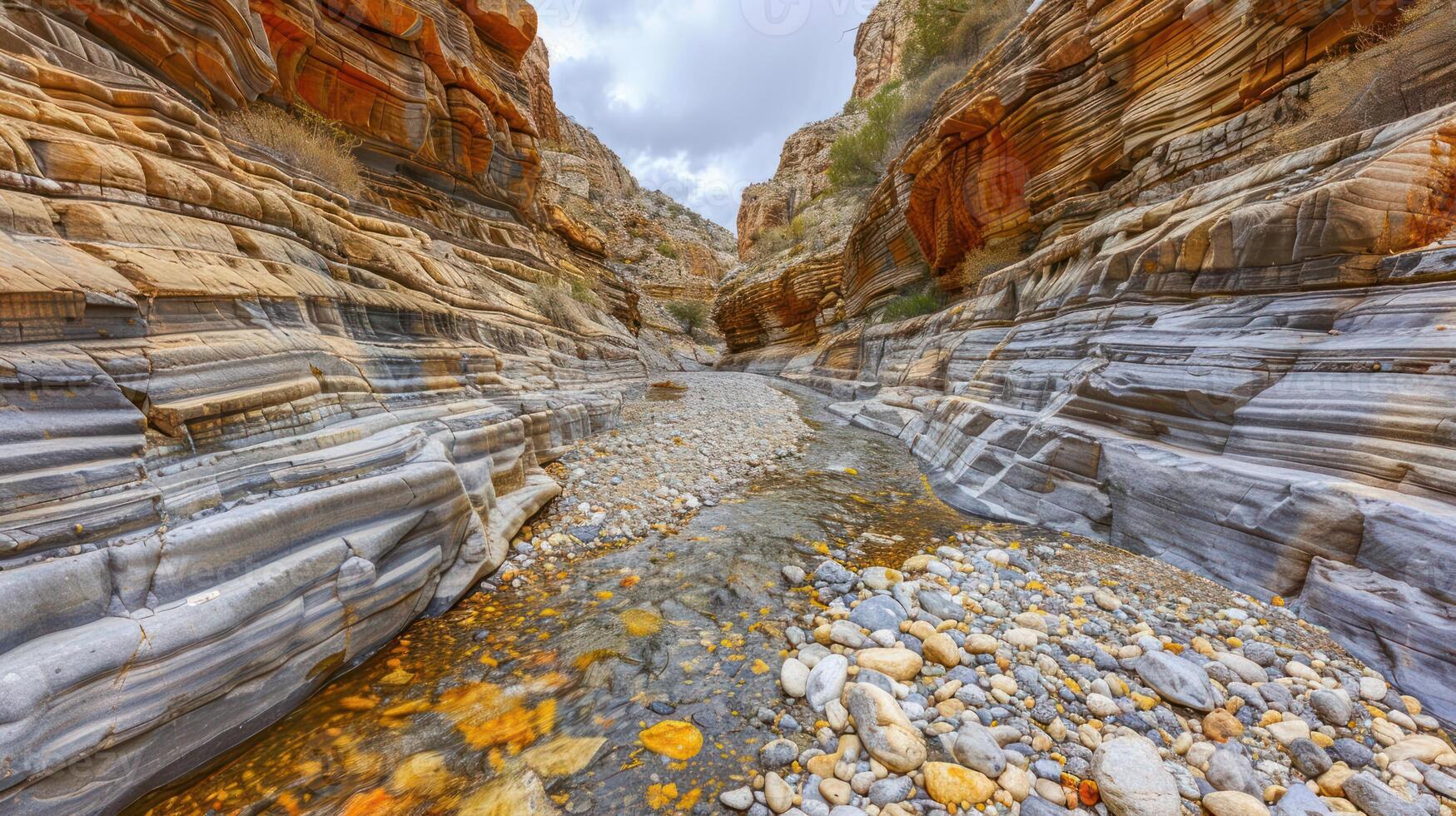A serene canyon landscape with layered rock formations and a flowing stream. photo