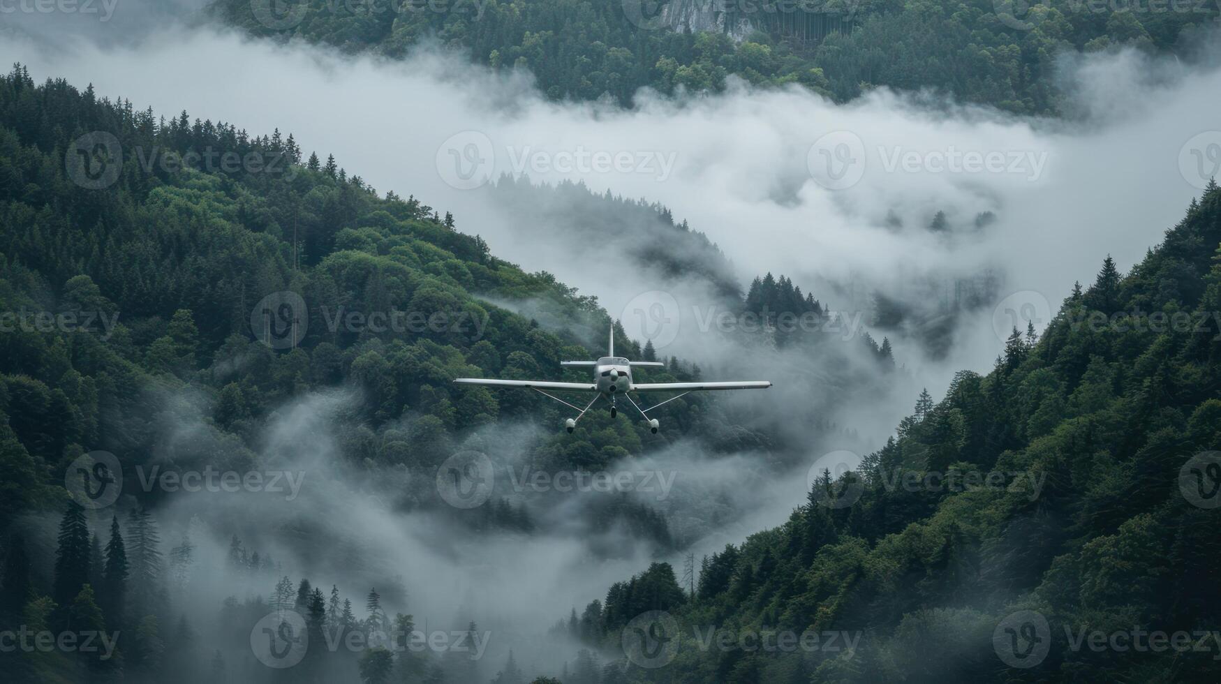 A small aircraft flying through a misty mountainous landscape surrounded by dense forests. photo