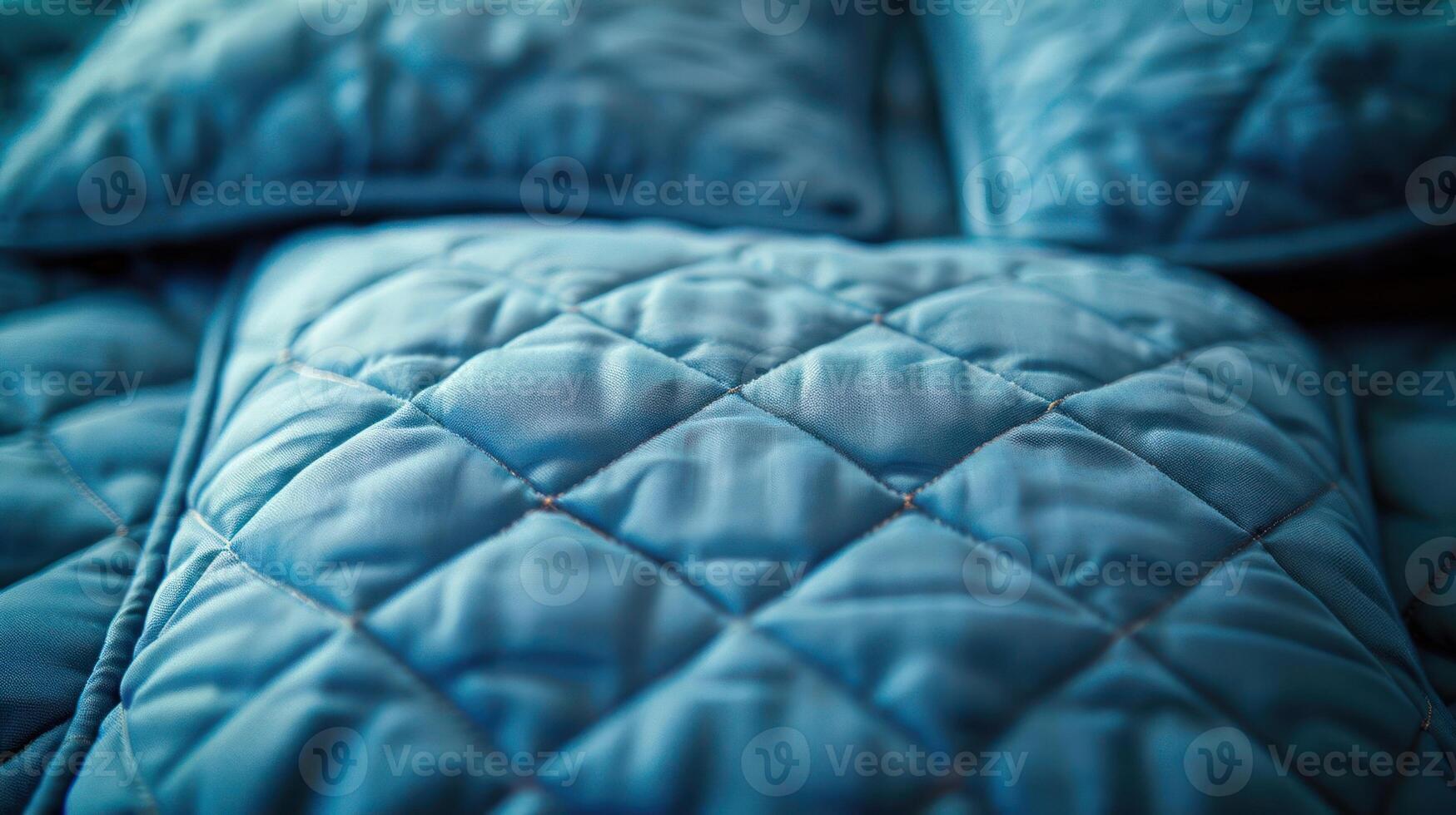 A close-up of a soft, quilted blue bedding set with decorative pillows. photo