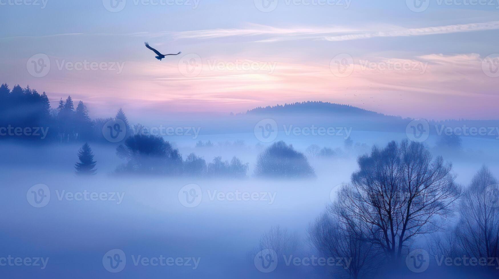 A serene landscape at dawn with mist and a bird soaring above the trees. photo