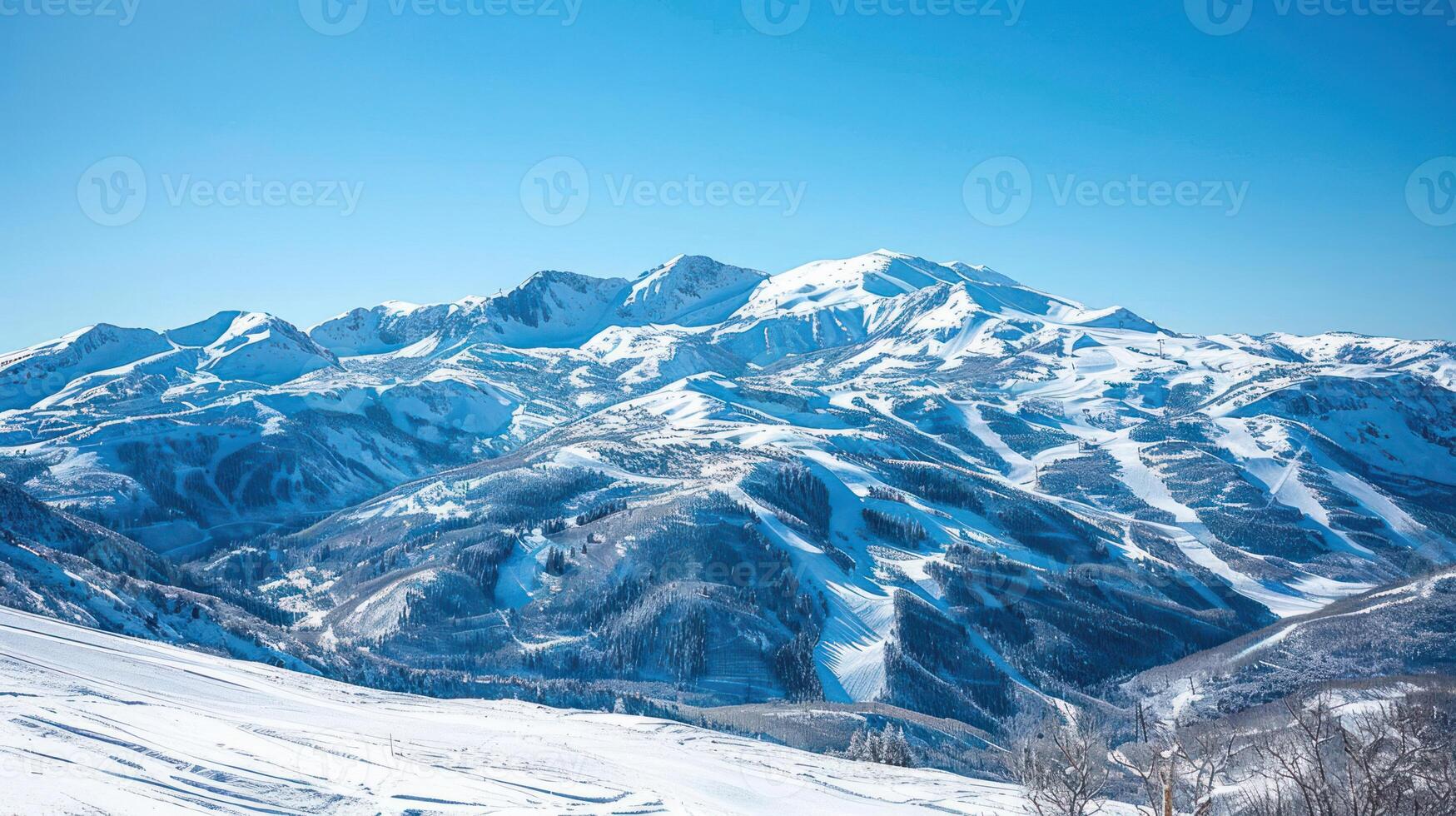 A panoramic view of snow-covered mountains under a clear blue sky. photo