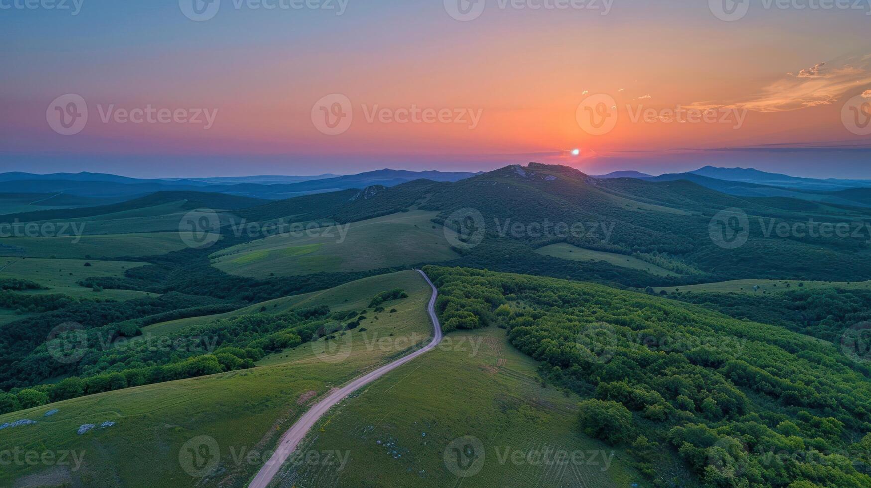 A serene landscape at sunset, showcasing rolling hills and a winding road. photo