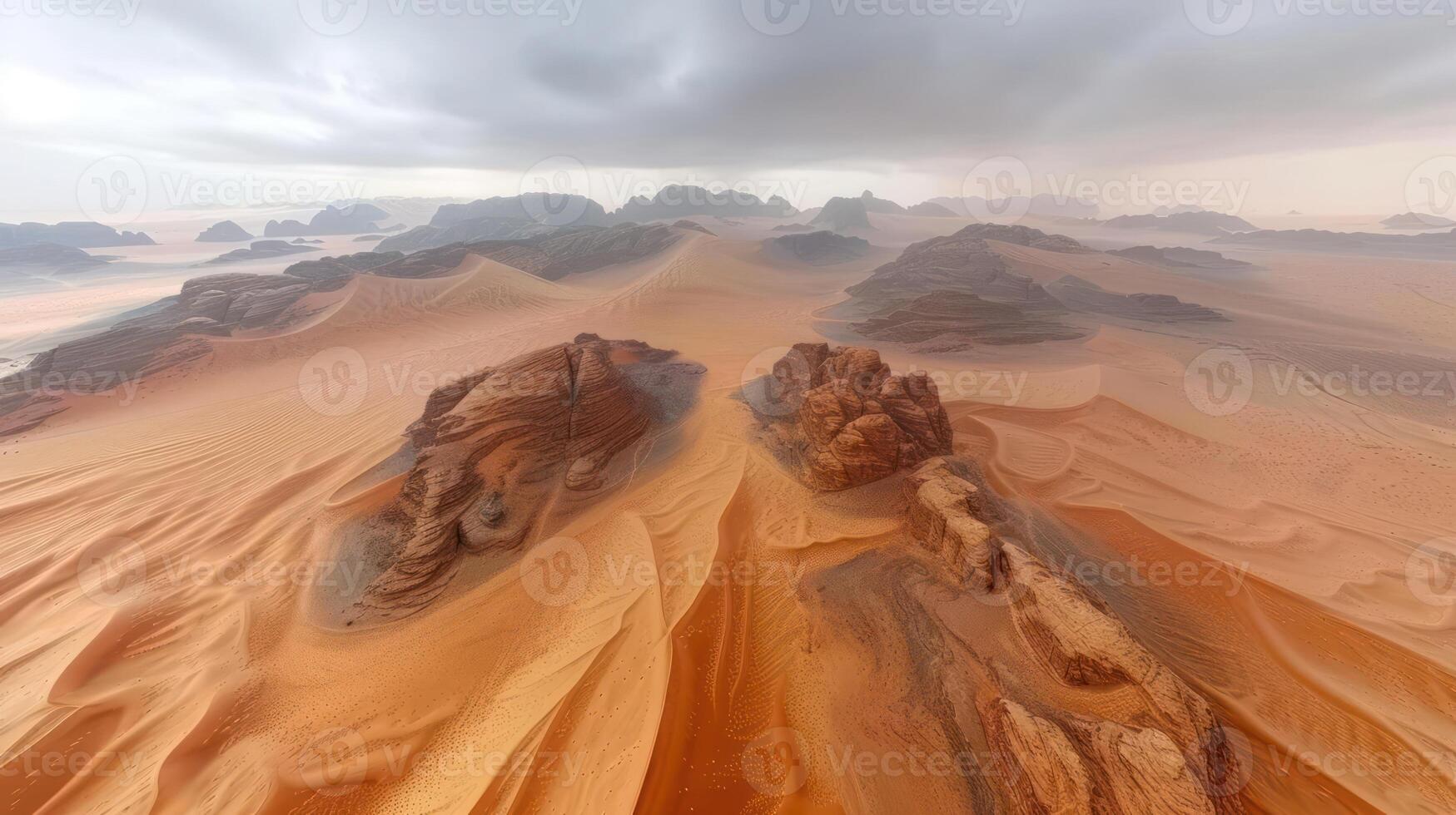 Aerial view of a vast desert landscape with sand dunes and rocky formations under a cloudy sky. photo