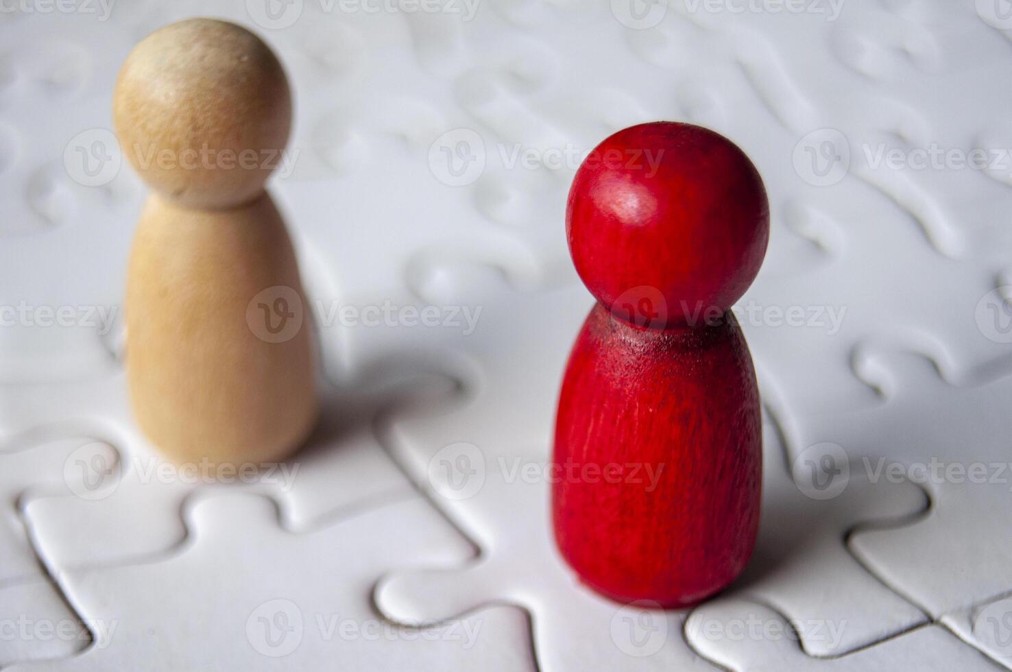 Close up of red and brown wooden dolls on jigsaw puzzle with customizable space for text photo