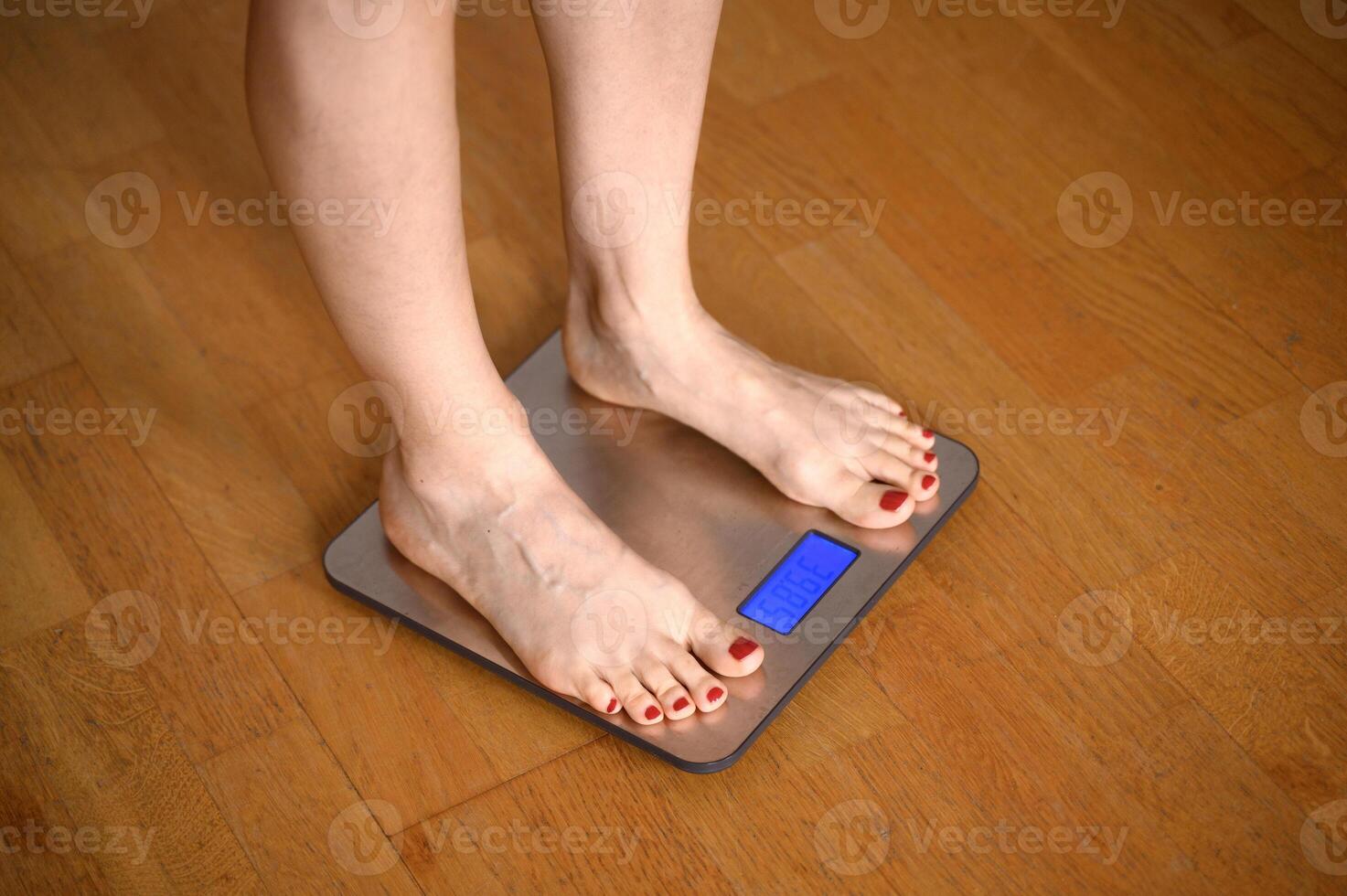woman feet with red nail polish on the bathroom scales photo