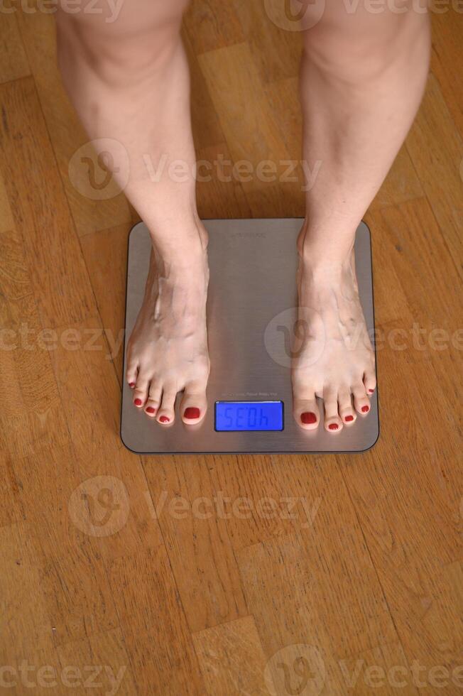 woman feet with red nail polish on the bathroom scales photo