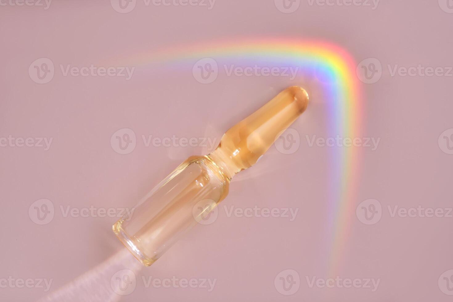 An ampoule with a medical product or cosmetic product on a pink background. photo