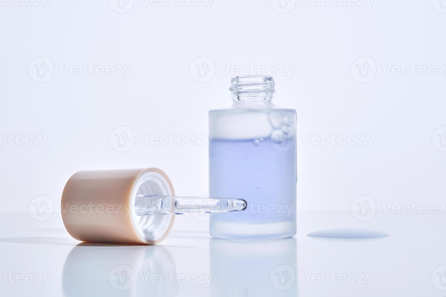 Cosmetic bottle, dropper and a drop of serum on a white background. photo