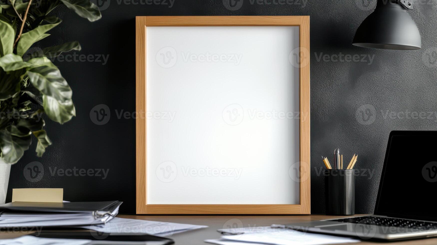 Mock up of a blank white frame on a desk with a laptop and a plant photo