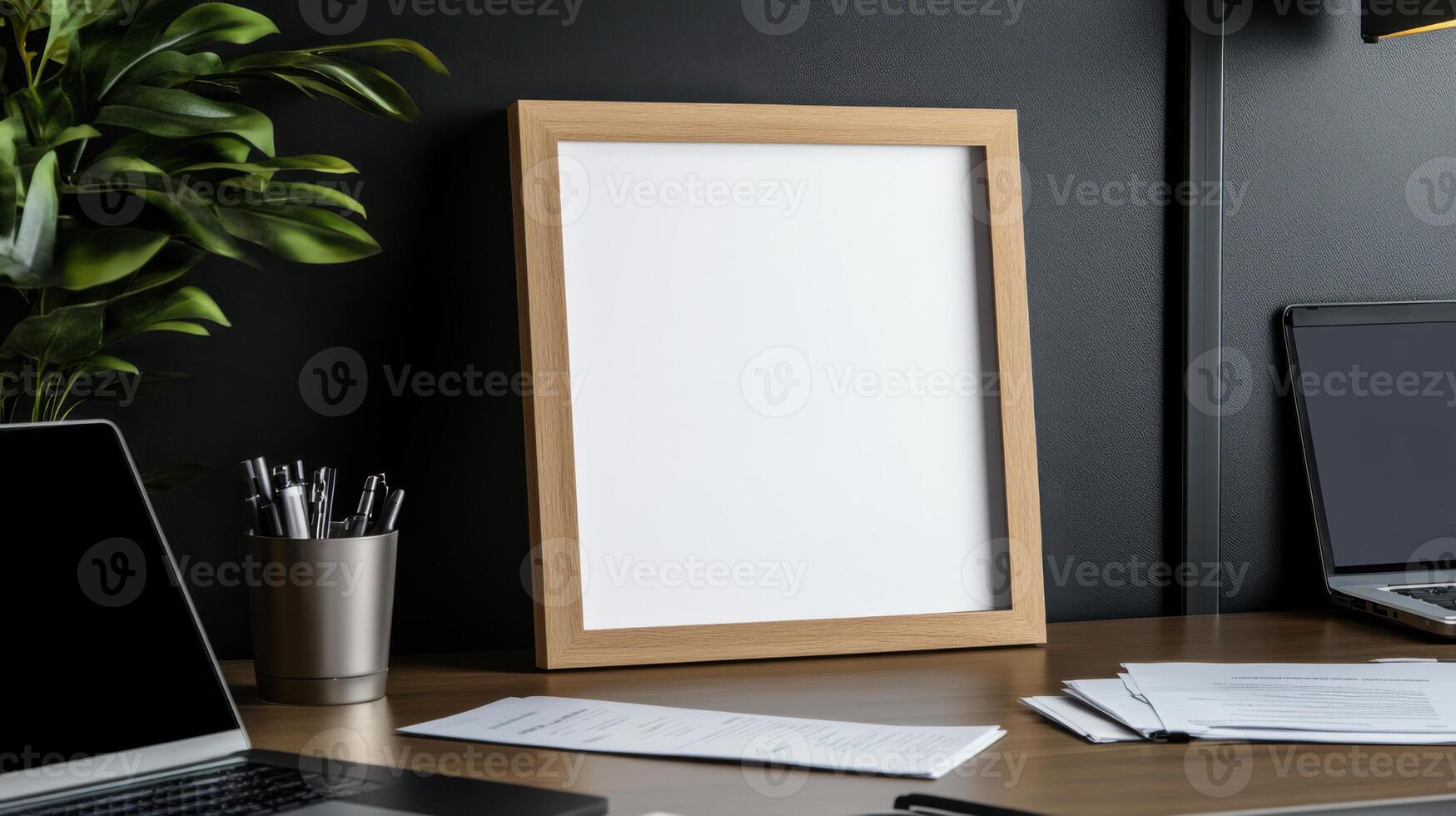 Mockup of a blank poster on a desk with a laptop and a plant photo