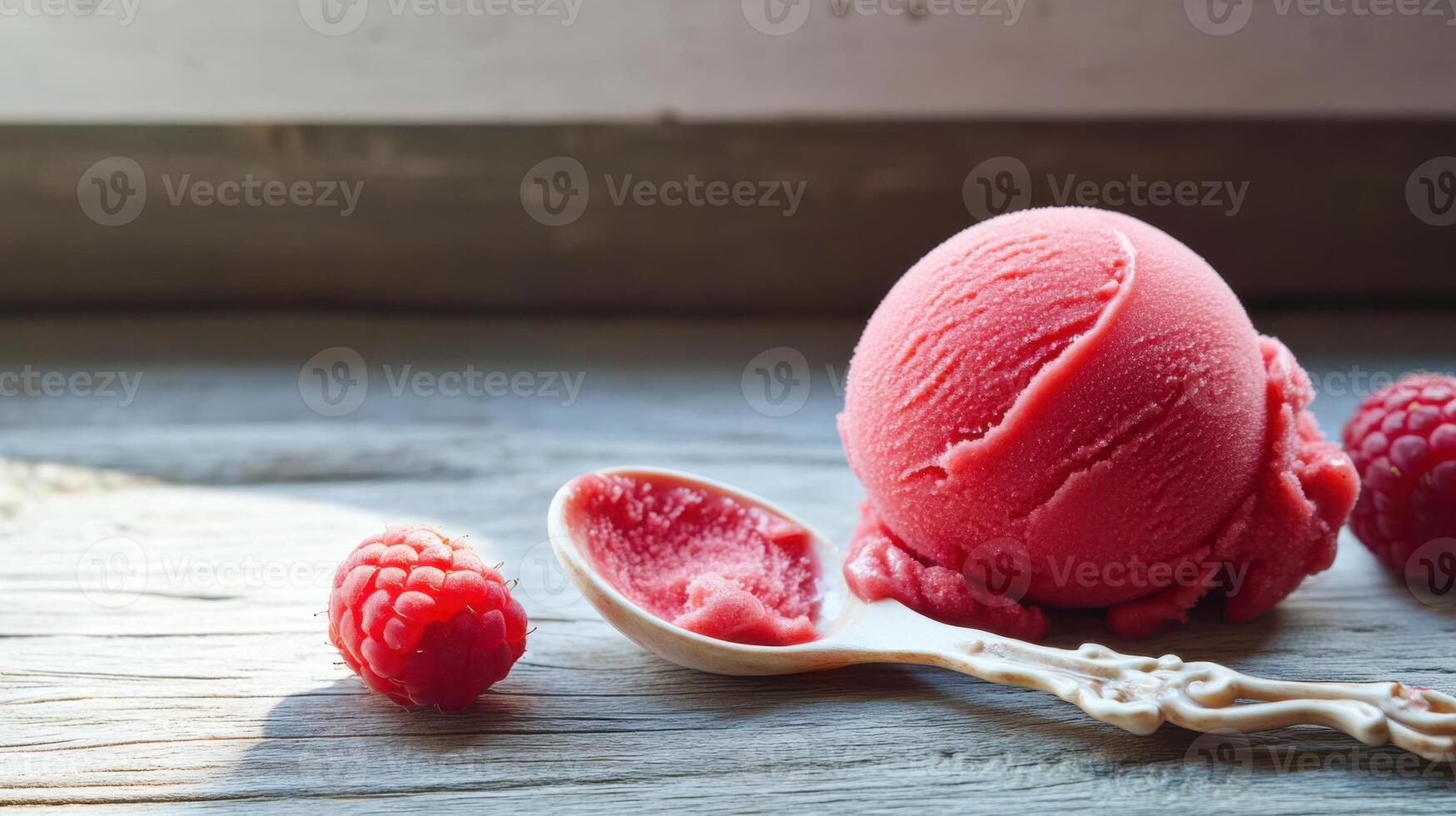 Raspberry ice cream with spoon on wooden table photo