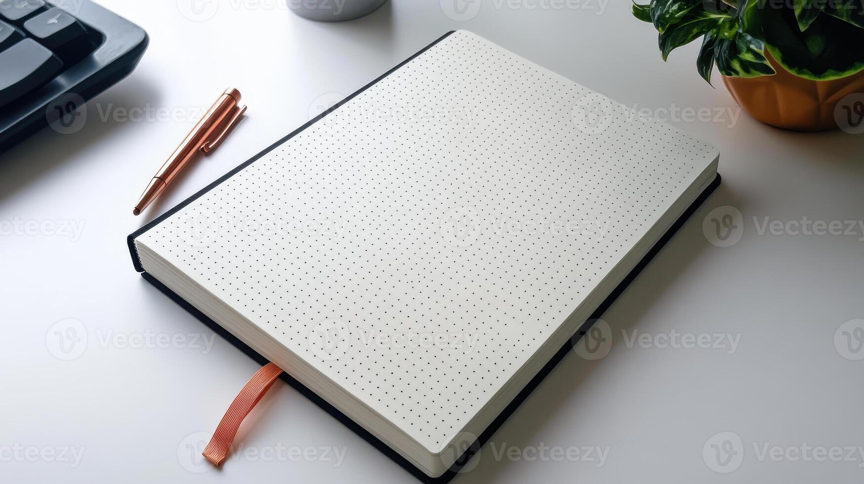 A notebook with a pen and a keyboard on a desk photo