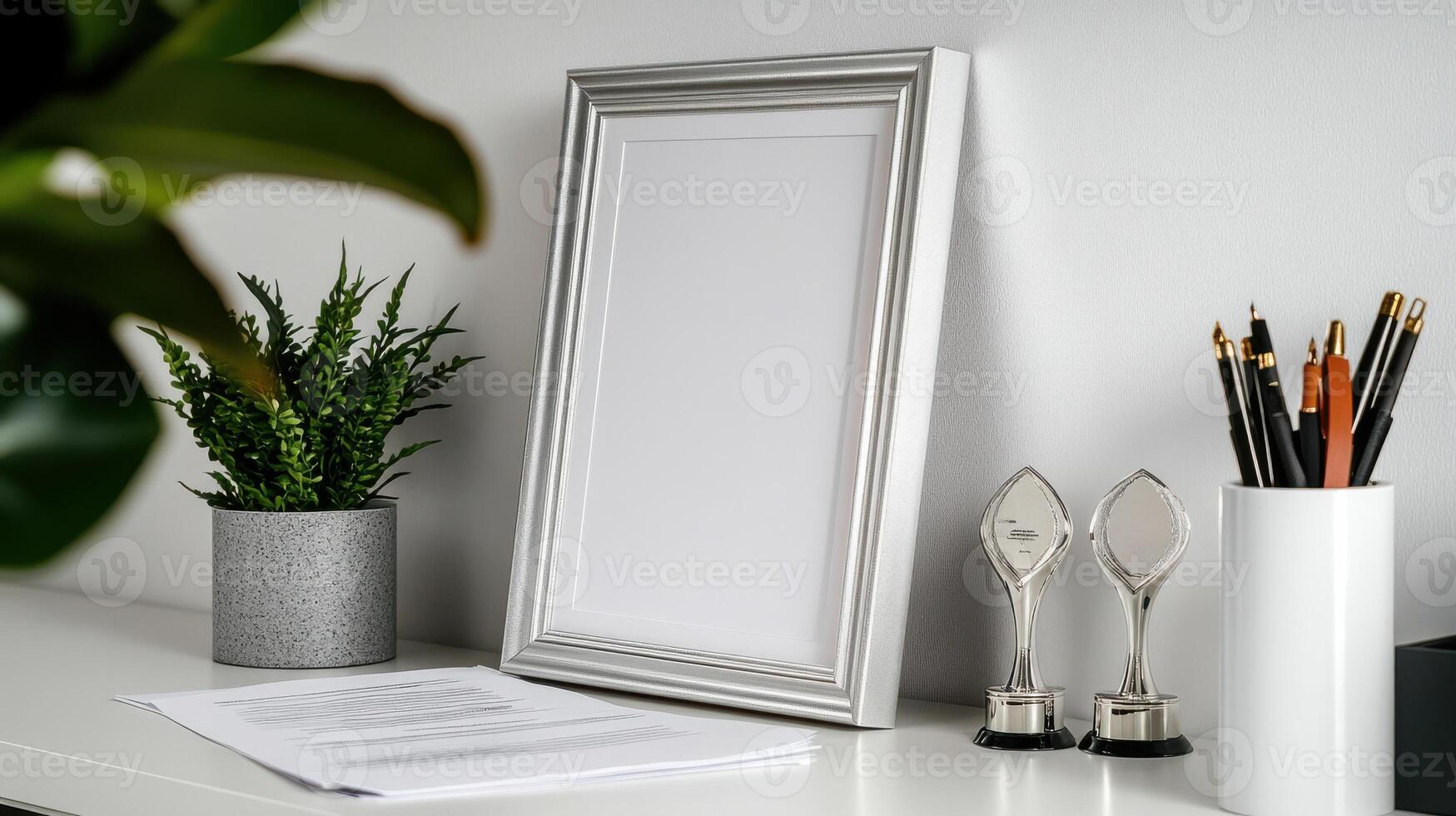 A white desk with a picture frame, a plant and a pair of scissors photo