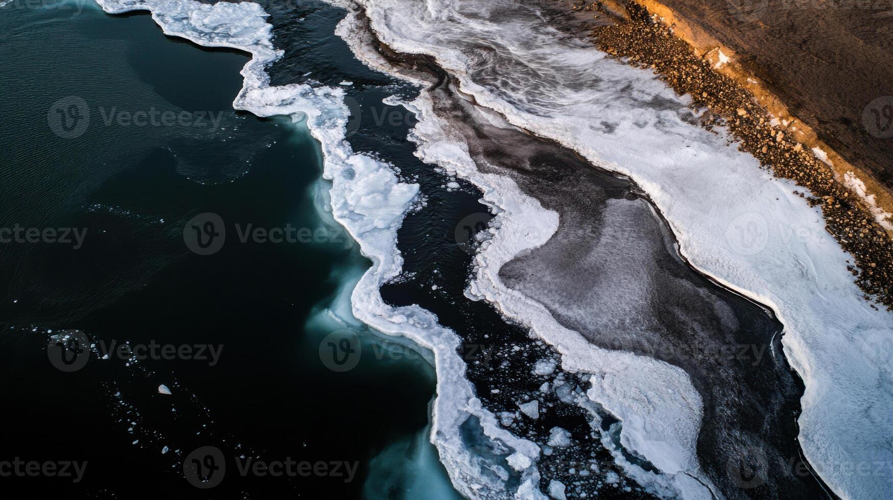 Melting ice forms unique patterns along dark water edge photo