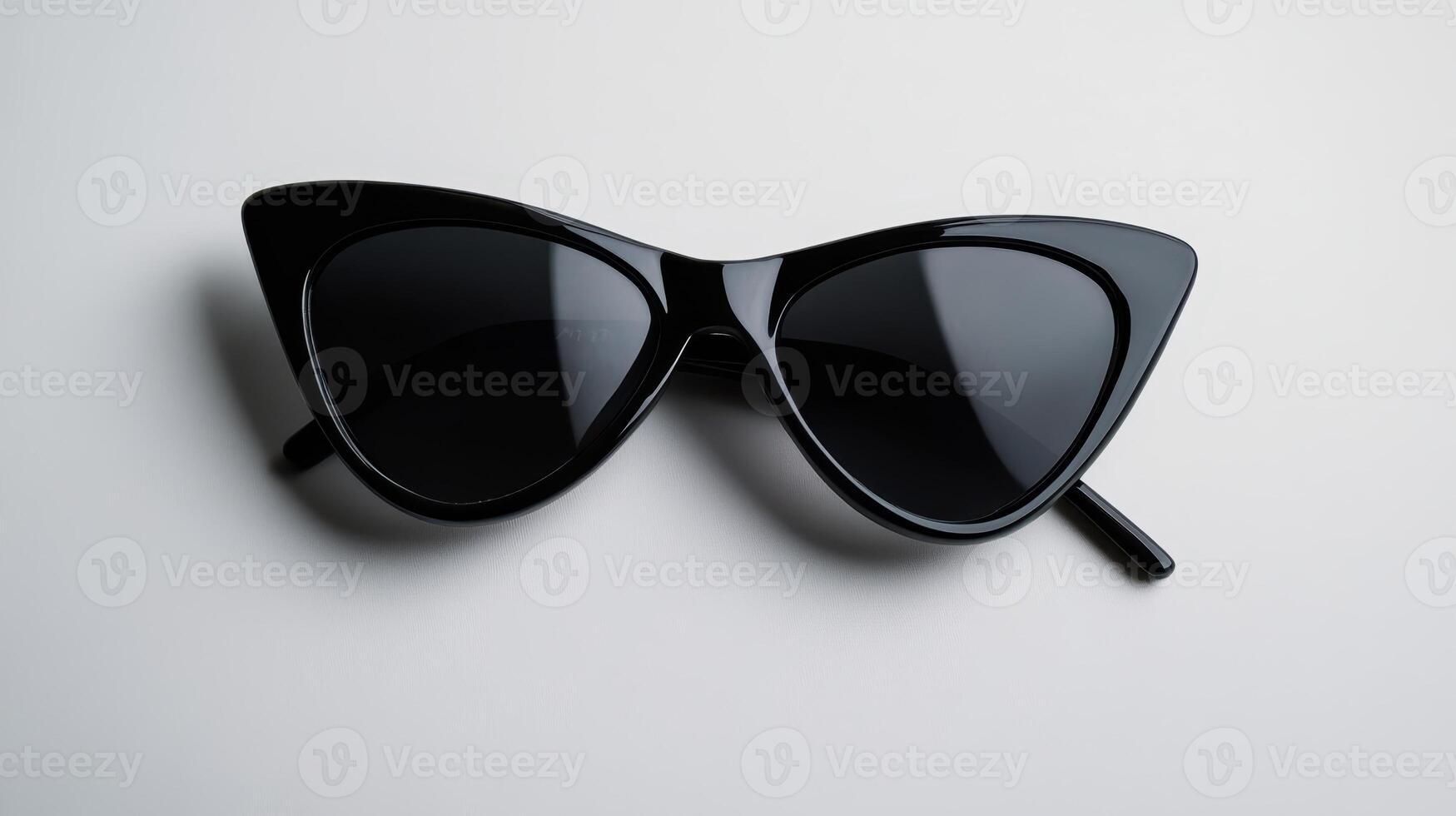 Stylish black cat-eye sunglasses placed on a clean white surface showcasing modern fashion accessories for summer trends photo