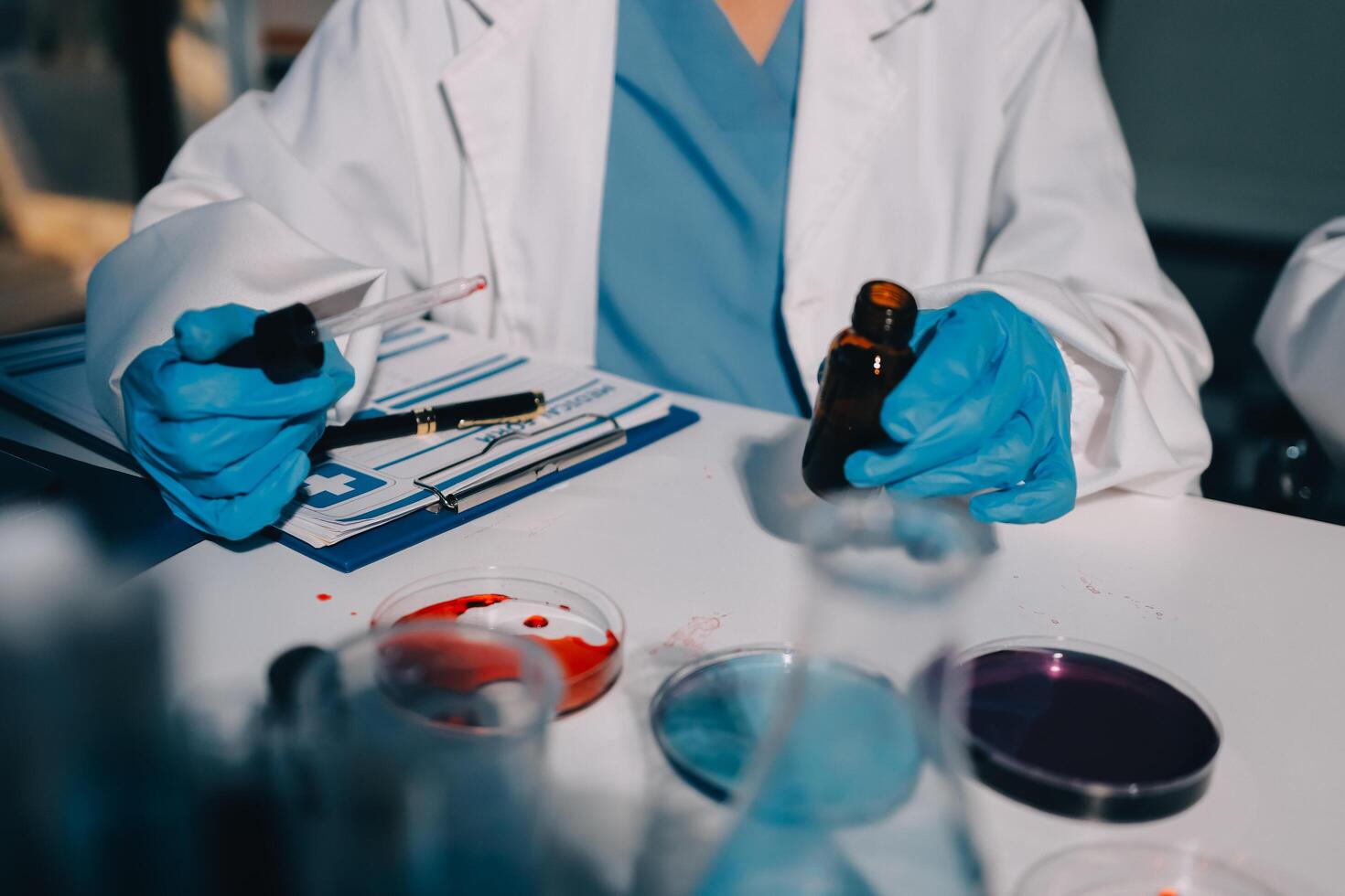A person in a lab coat and gloves holding a vial photo