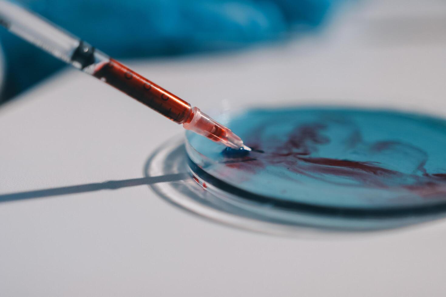 A person holding a syringe and a red liquid photo