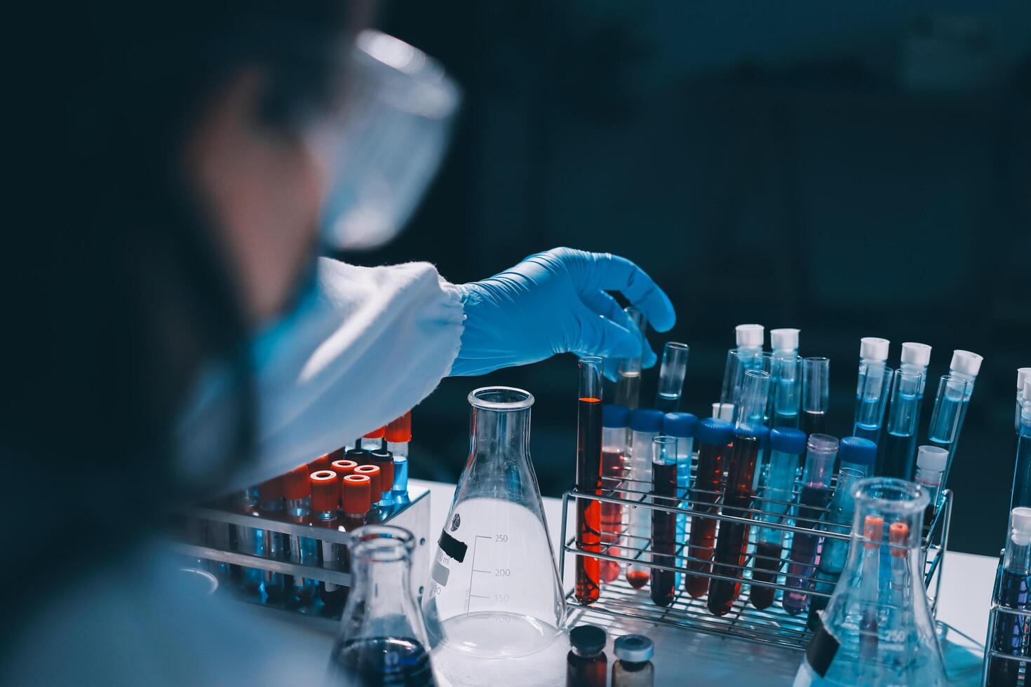 A person in a lab coat is holding a test tube photo