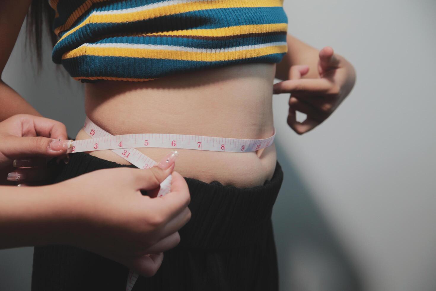 A woman measuring her waist with a tape measure photo