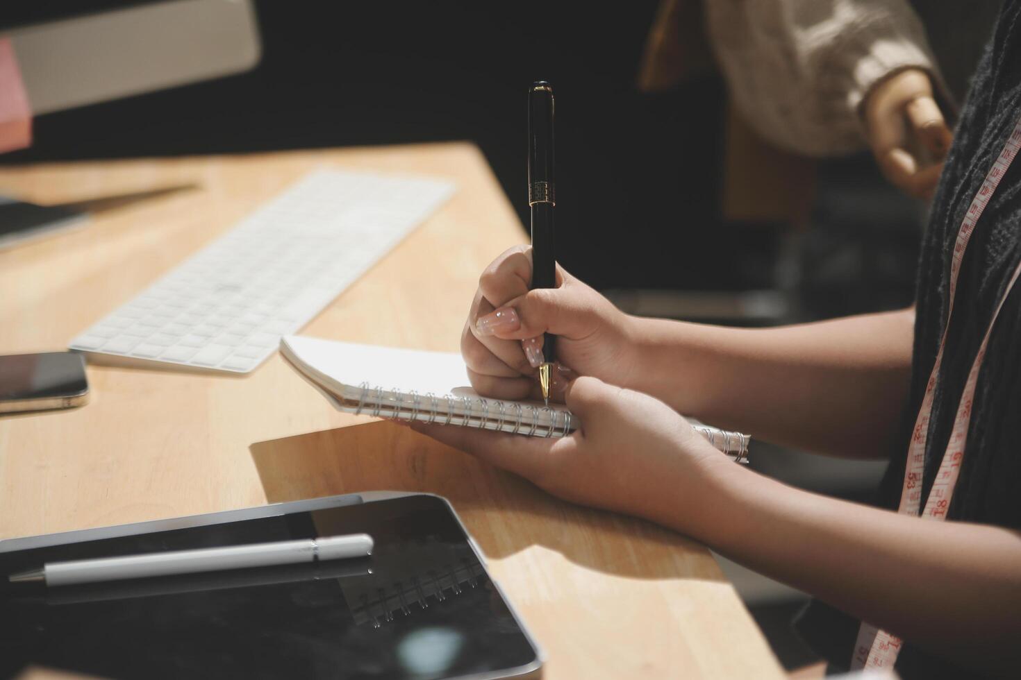 A person writing on a notebook with a pen photo