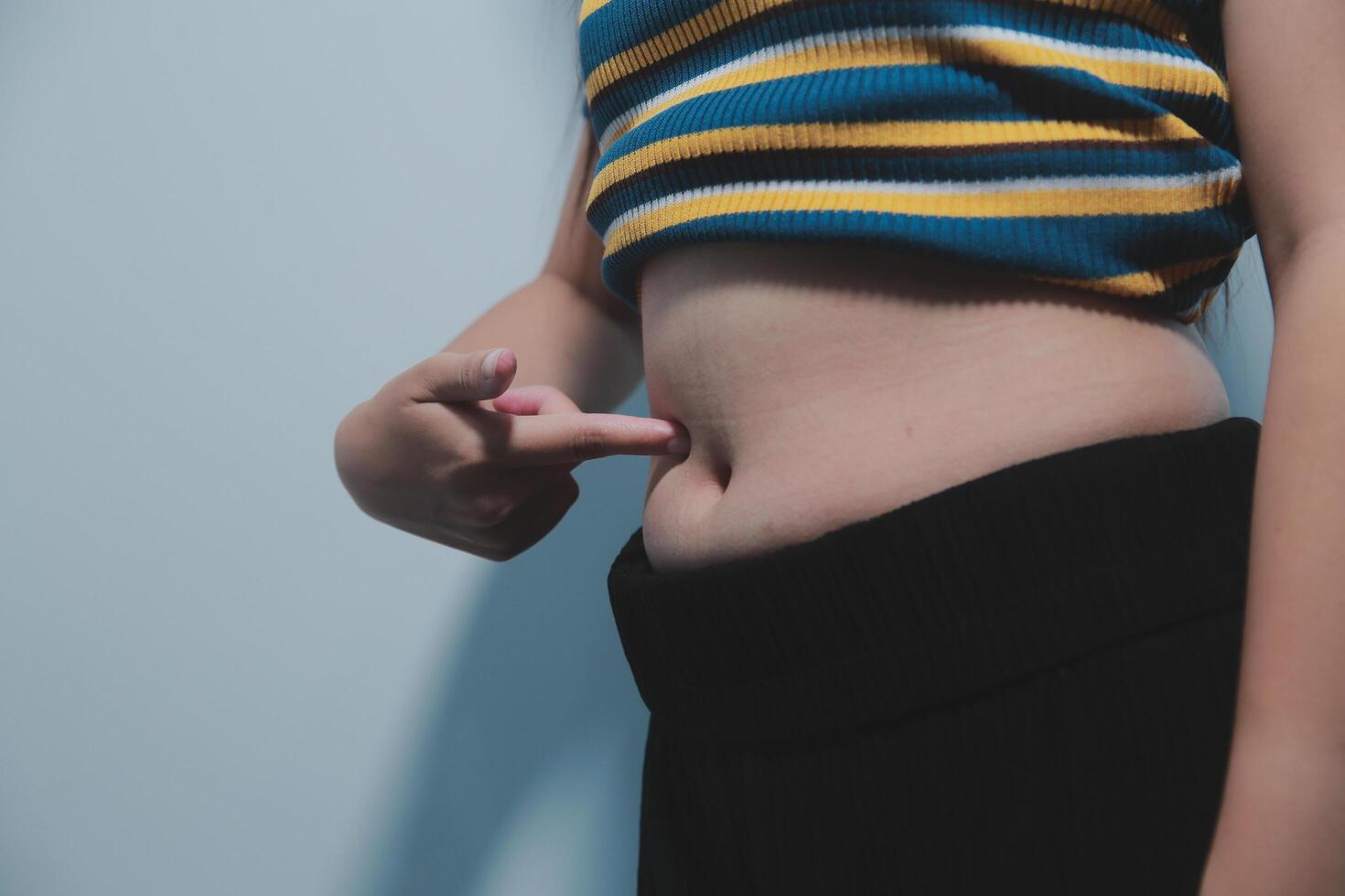 A woman with a small belly pointing to her stomach photo