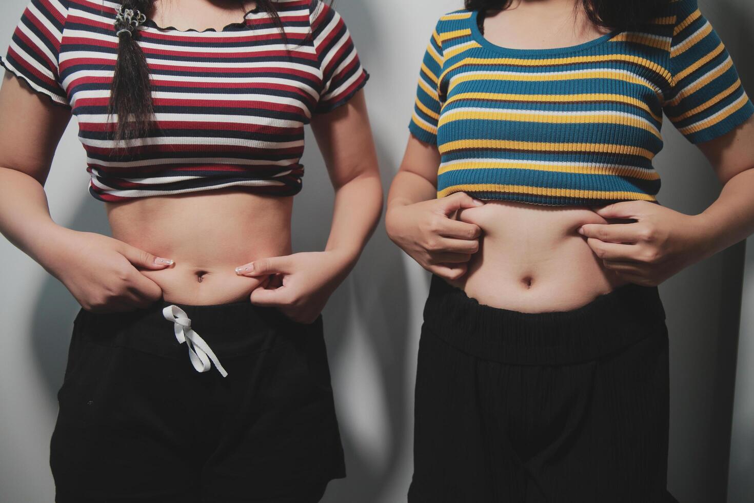Two women standing next to each other with their stomachs photo