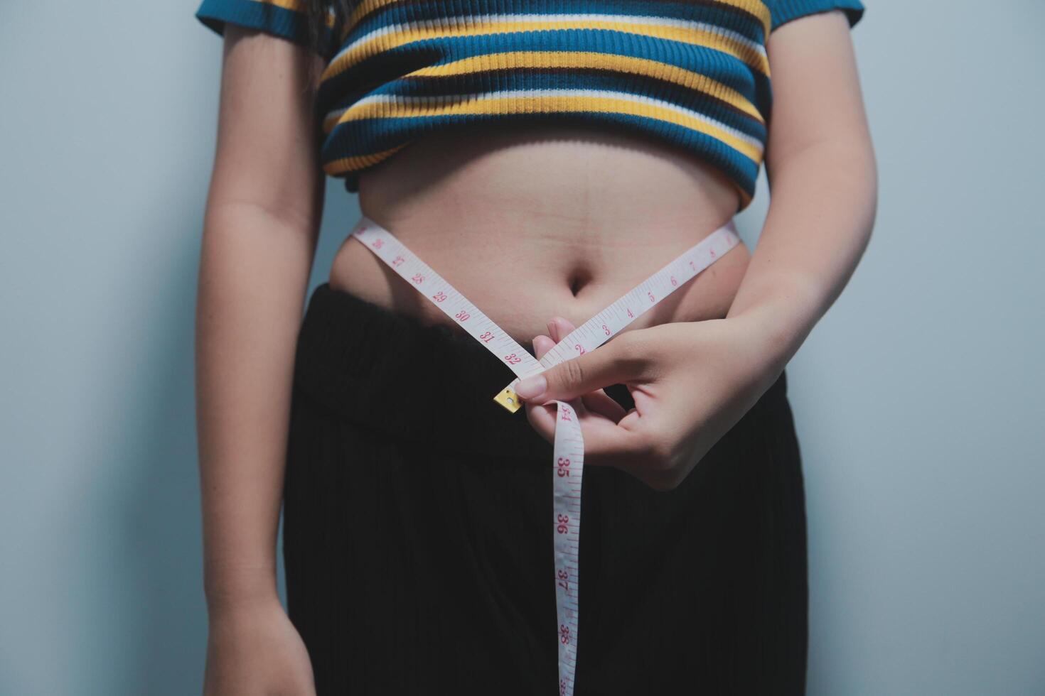 A woman is holding a measuring tape around her waist photo