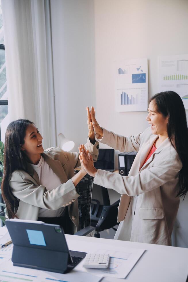 Two women in business attire high five each other photo